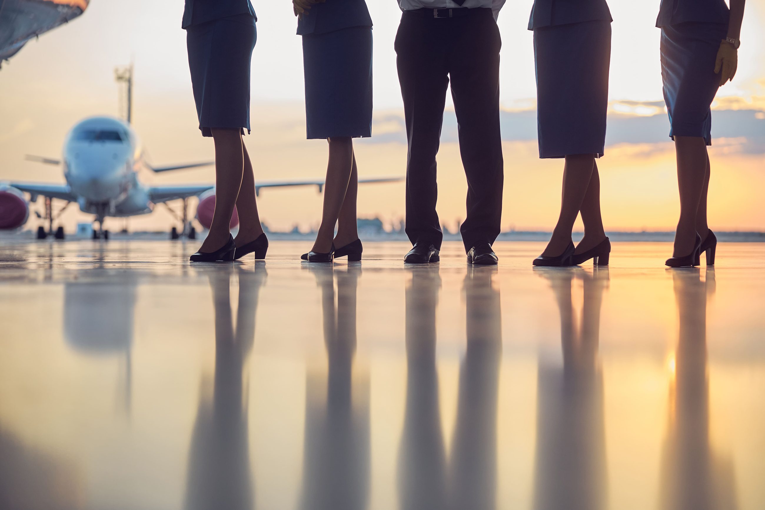 Comissárias e avião ao entardecer em viagem corporativa